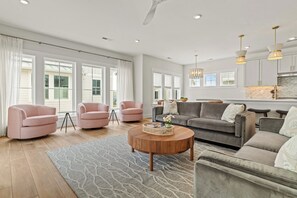 A spacious living room with a grey sofa, pink armchairs, and a wooden coffee table.