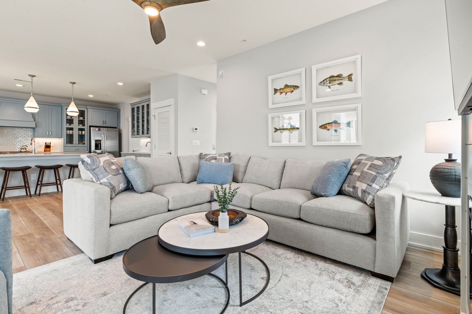 A modern living room with a grey sectional sofa, a coffee table, and a kitchen in the background.