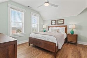 A bedroom with a large bed, two bedside tables with lamps, and a ceiling fan. - Moonlit Manor - Pets Welcome + Private Pool (Kill Devil Hills)