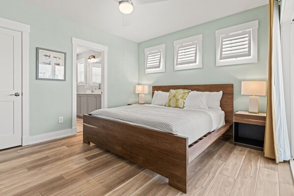 Un dormitorio con una cama de madera, ropa de cama blanca y dos lámparas de noche.
