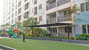 Un edificio residencial con balcones, una zona de juegos para niños y un césped bien cuidado.