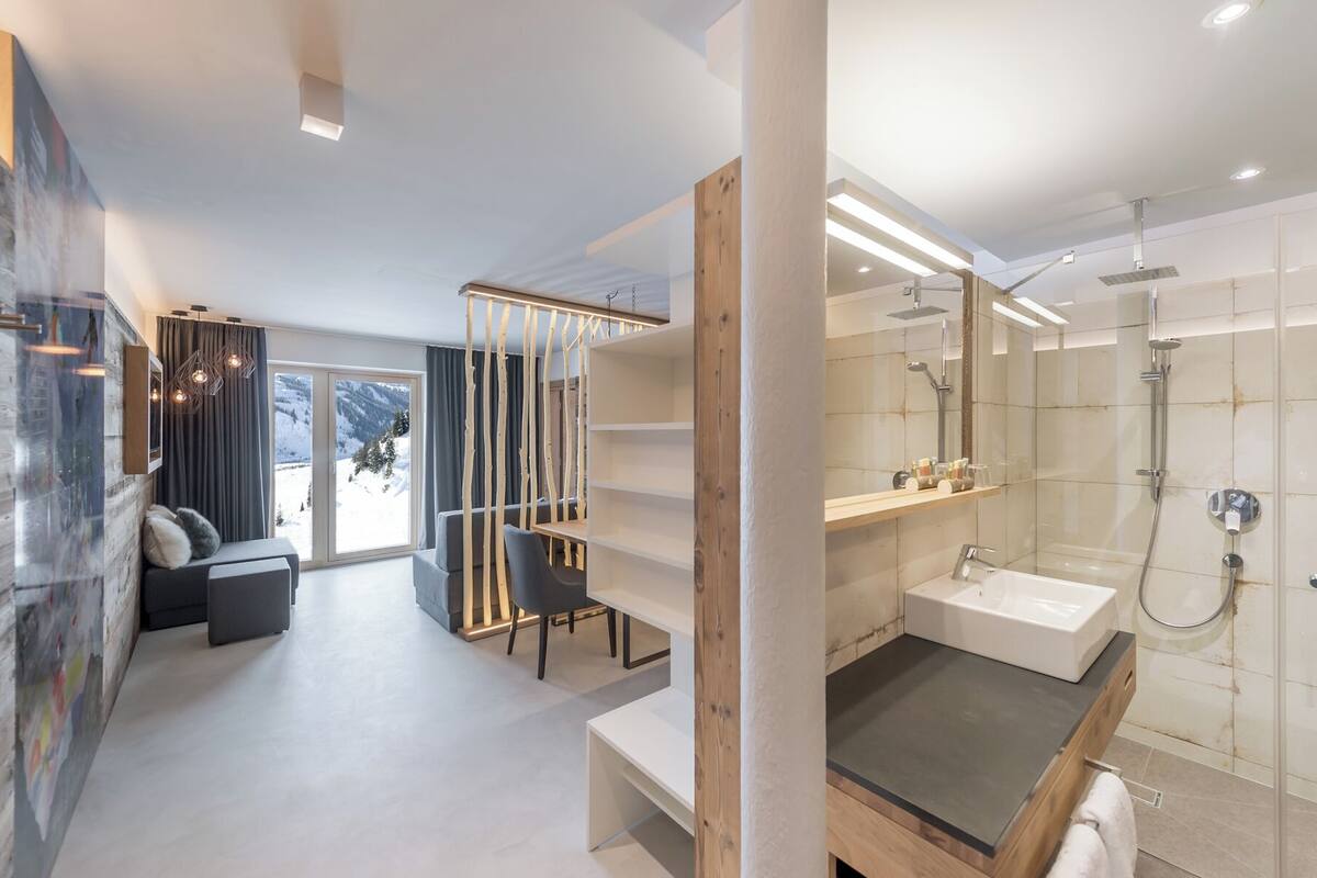 Un baño moderno con cabina de ducha de vidrio, lavabo empotrado y mueble de tocador de madera.