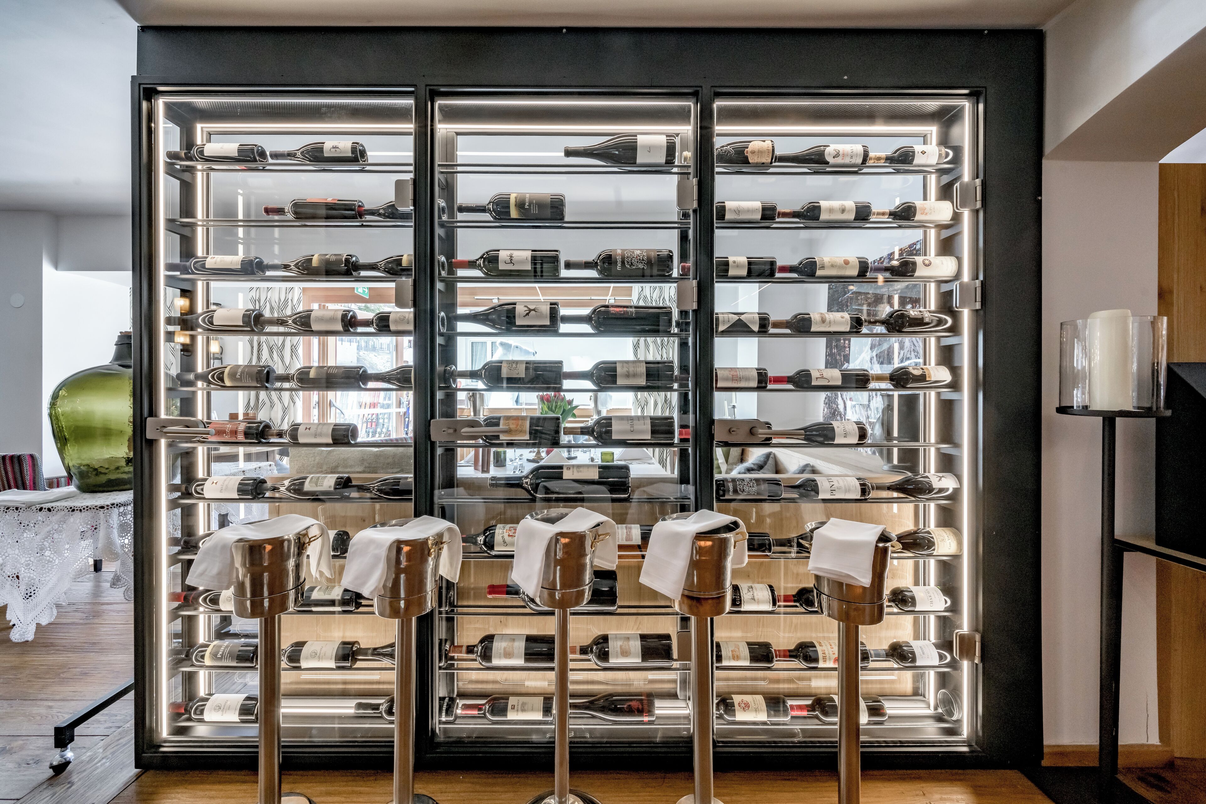 A wine cellar with multiple shelves of bottles and a wine rack in the foreground.