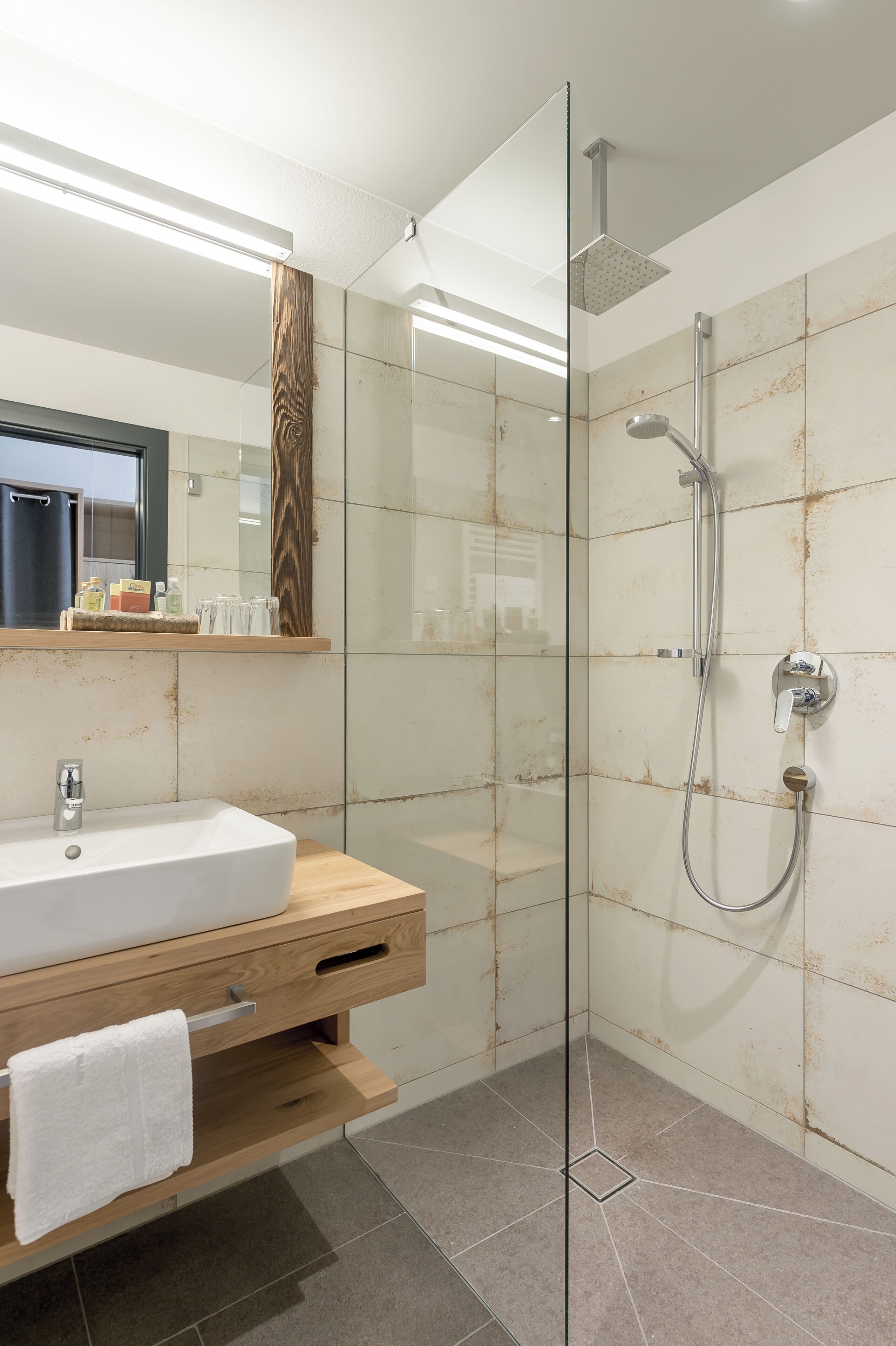 Une salle de bain moderne avec une douche à parois de verre, un meuble-lavabo en bois et un miroir au-dessus.