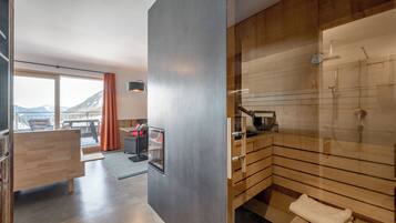 Un baño moderno con cabina de ducha acristalada, muebles de madera y vistas a montañas a través de amplias ventanas.