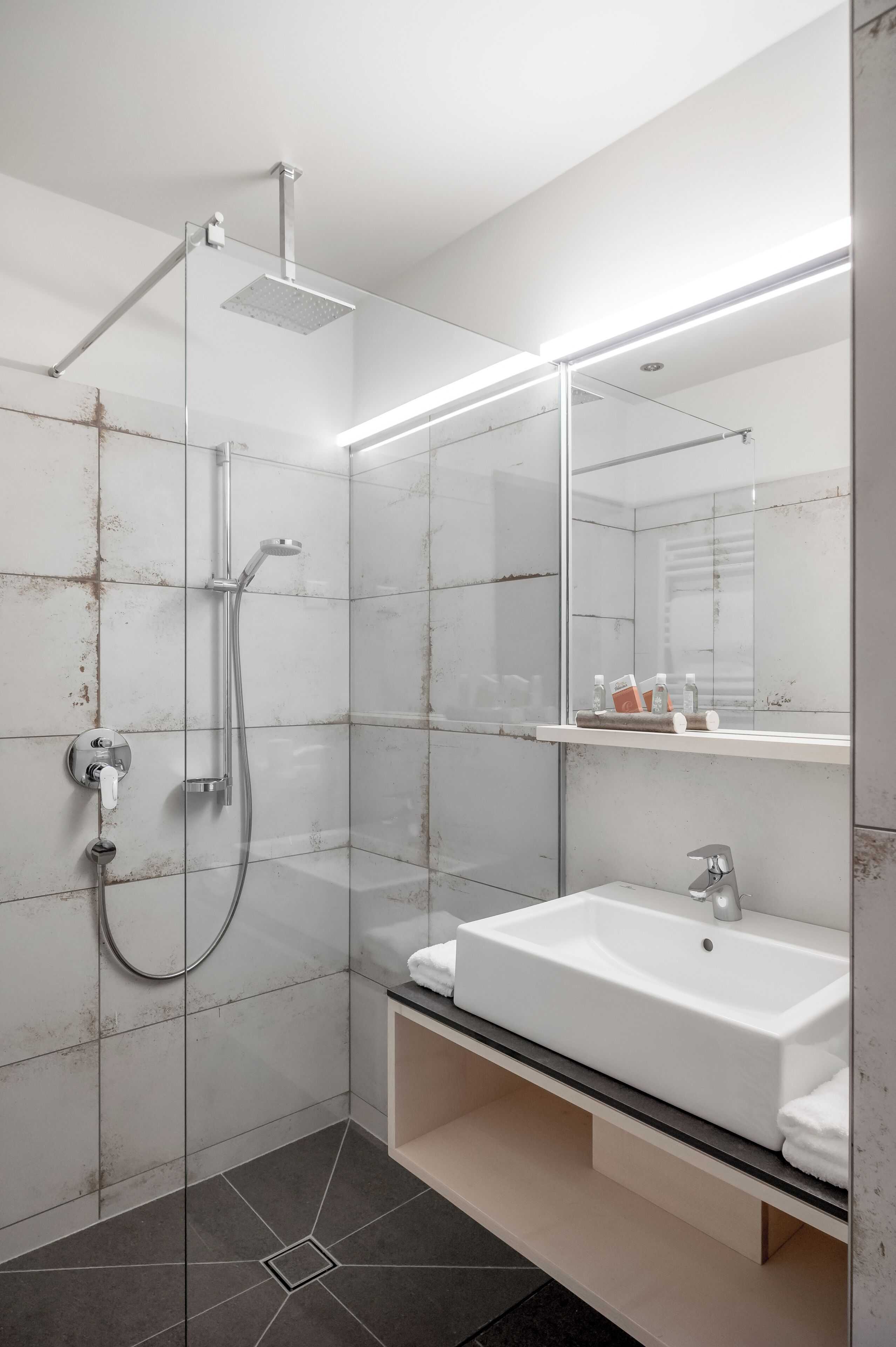 A modern bathroom with a glass-enclosed shower, a white sink, and a mirror above it.