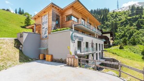 Un hôtel moderne avec une façade en bois, un balcon et une vue sur une colline verdoyante.