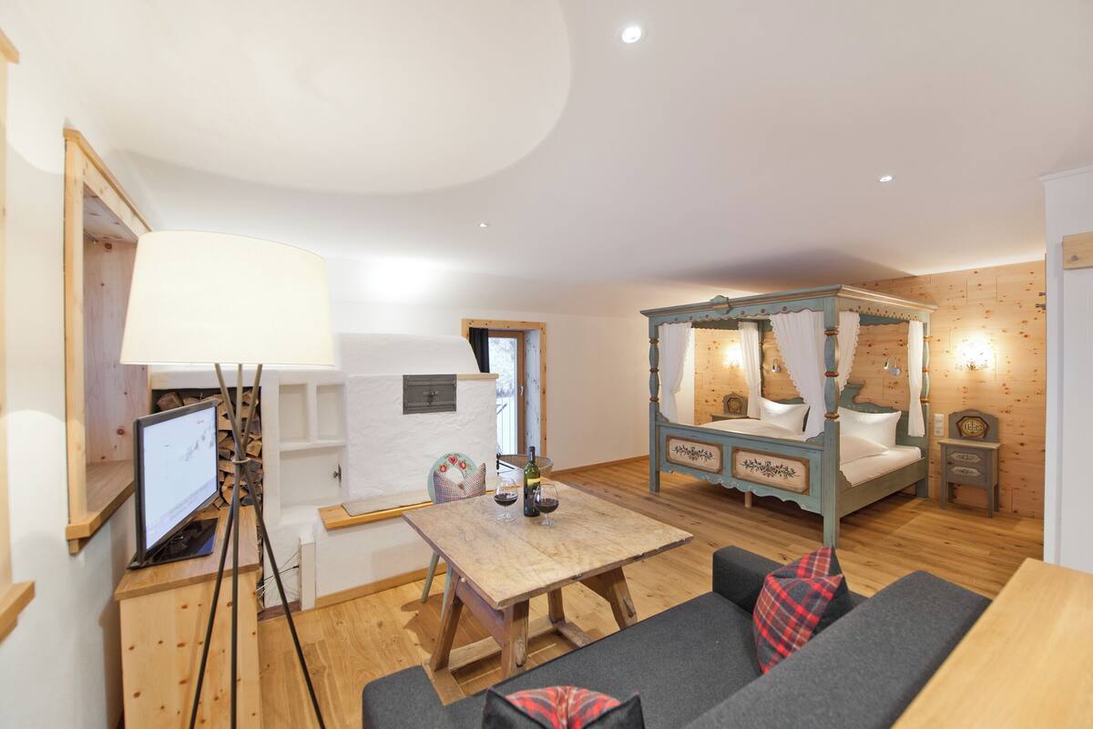 Una habitación acogedora con piso de madera, una cama con dosel, un escritorio con computadora y un sofá.