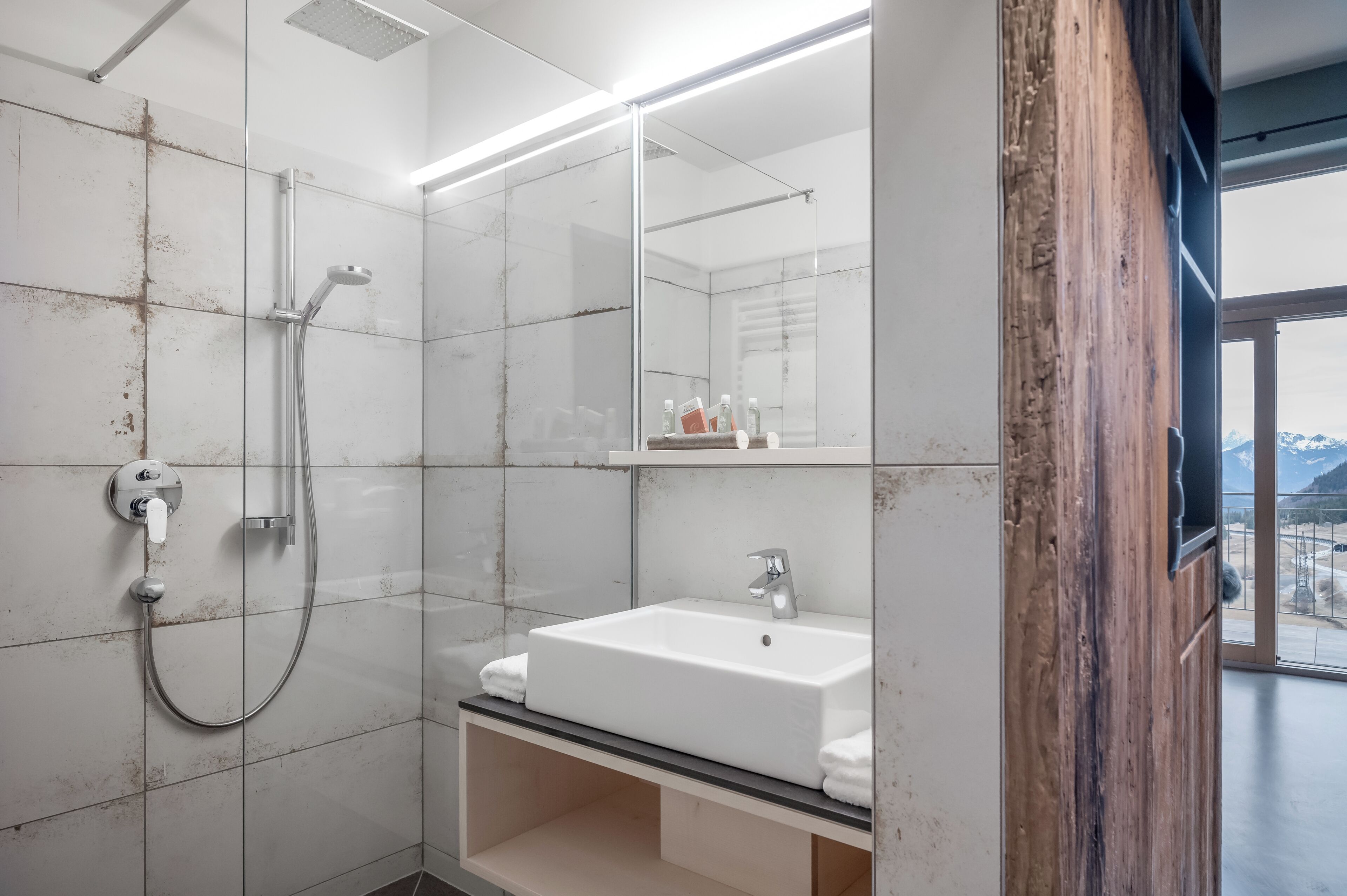 Une salle de bain moderne avec une douche à parois de verre, un lavabo blanc et un grand miroir.