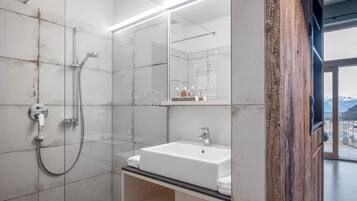 Une salle de bain moderne avec une douche à parois de verre, un lavabo blanc et un grand miroir.