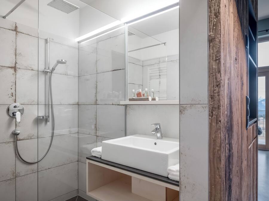 Une salle de bain moderne avec une douche à parois de verre, un lavabo blanc et un grand miroir.