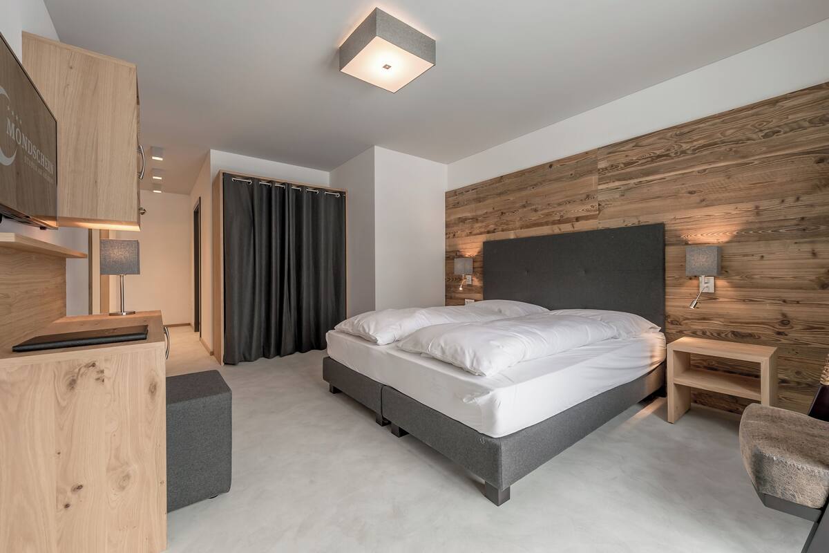 Un dormitorio moderno con cama, escritorio, silla y una pared de acento de madera.