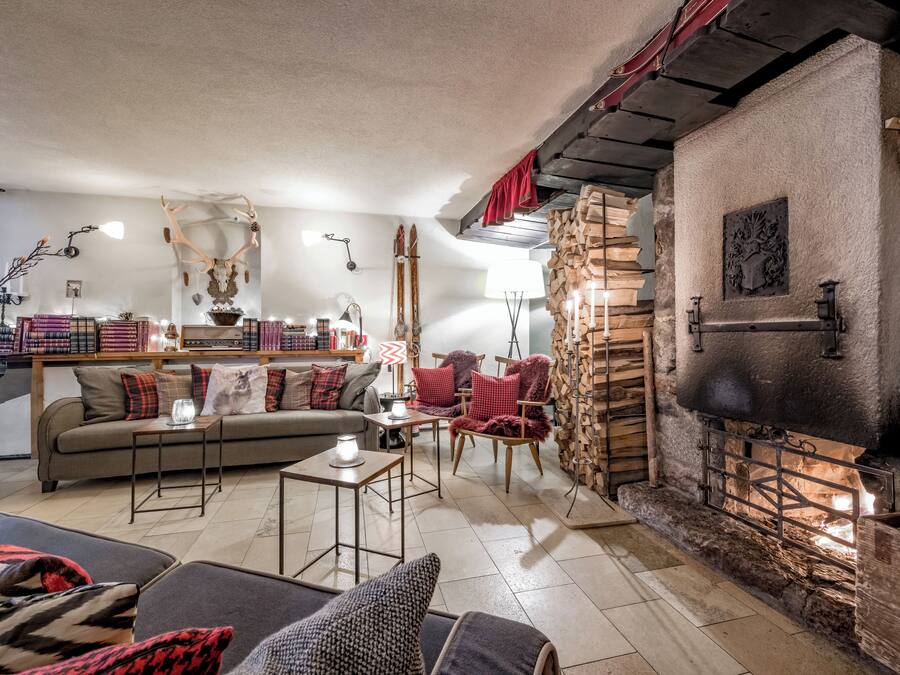 Een gezellige woonkamer met een open haard, een bank, een salontafel en een boekenkast.