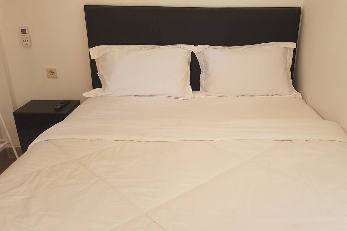 A neatly made bed with a black headboard and white bedding.