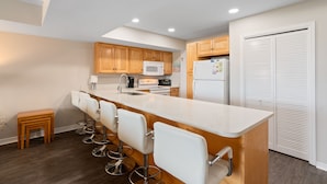 A modern kitchen with a central island, wooden cabinets, and a white refrigerator. - Gulf-view condo steps away from beach! 2 Community Pools!  (Dauphin Island)