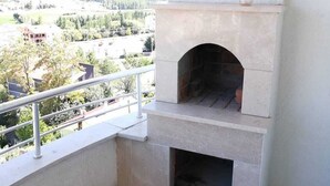 Ein Balkon mit Kamin aus Stein und Blick auf ein bewaldetes Gebiet.