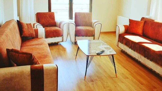 Ein Wohnzimmer mit zwei Sofas, einem Couchtisch und einem Fenster mit Vorhängen.