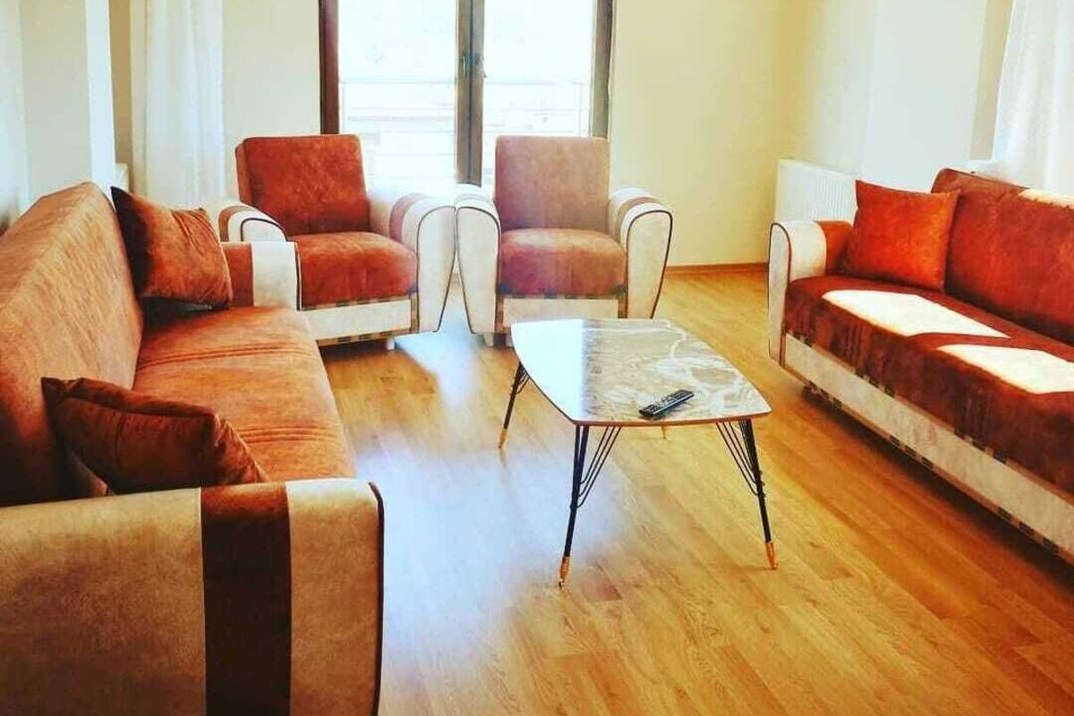 Ein Wohnzimmer mit zwei Sofas, einem Couchtisch und einem Fenster mit Vorhängen.