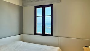 Ein Schlafzimmer mit großem Fenster, einem Bett und einem Deckenlüfter.