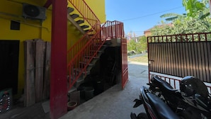 Um edifício amarelo com uma escadaria vermelha que leva a uma área coberta.