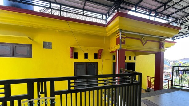 Um edifício amarelo com guarda-corrimão preto, uma escadaria e vista da região circundante.
