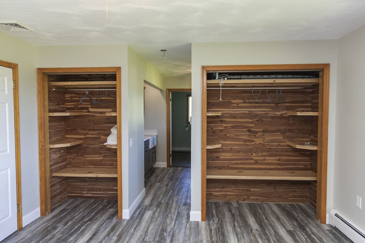 A hallway with wooden closet spaces and a kitchen area in the background.
