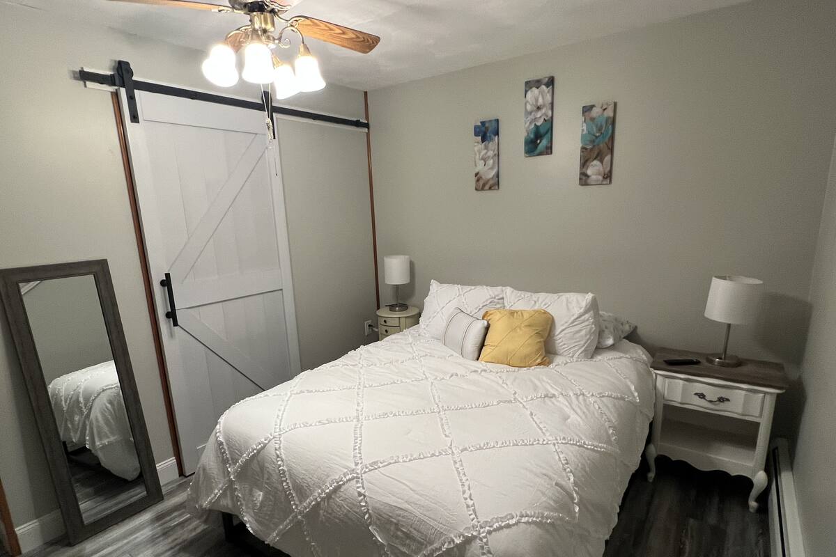 A bedroom with a bed, bedside tables, a ceiling fan, and artwork on the wall.