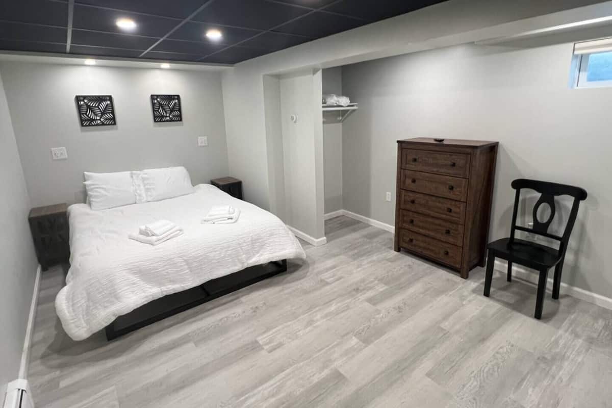 A bedroom with a bed, a dresser, a chair, and a closet.