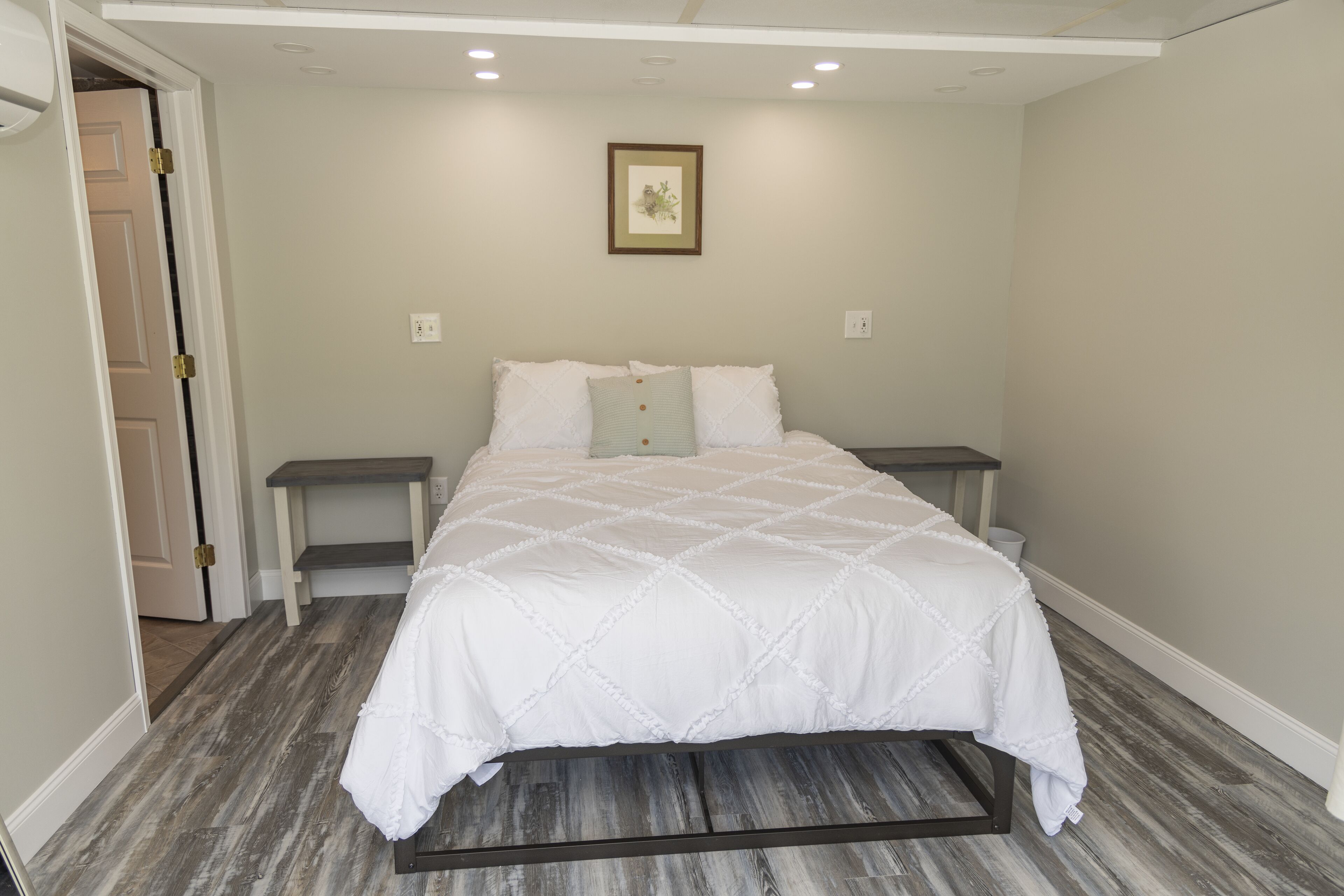A bedroom with a bed, bedside tables, a door, and a wall-mounted picture.