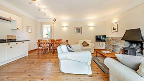Una sala de estar con sofá, televisión, chimenea y comedor con mesa y sillas.