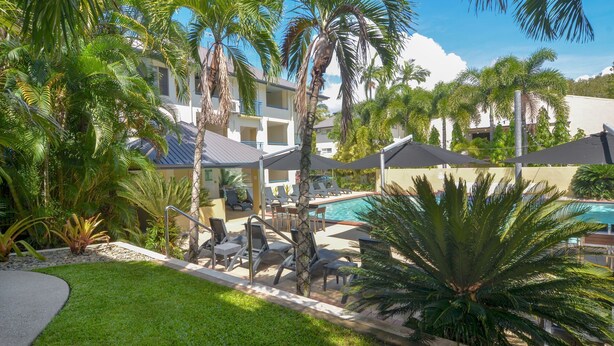 Un resort con piscina, sillones de descanso y palmeras.