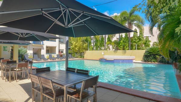 Relax by the pool surrounded by lounge chairs and shaded by umbrellas.