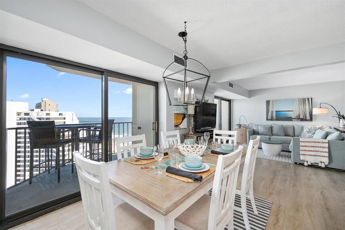 Een moderne woonkamer met een eethoek, grote ramen, een balkon en een televisie.