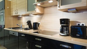 A modern kitchen with wooden cabinets, a stainless steel range hood, a coffee maker, and a toaster. - Villa Doria  (Luxembourg City)