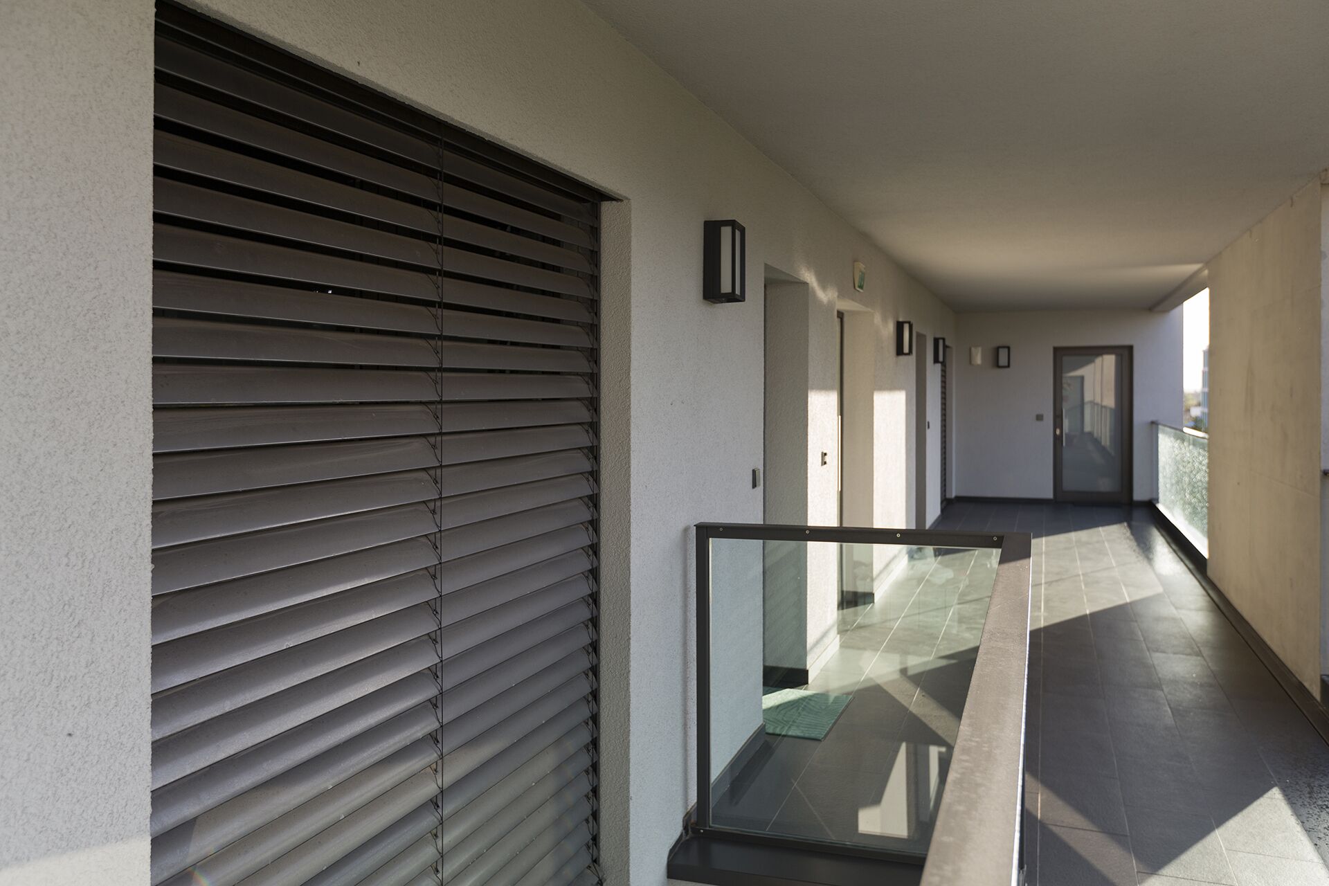 A corridor with a sliding door, a glass door, and a view of a building outside.