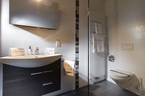 Un baño con tocador, inodoro y zona de ducha.
