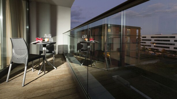 A balcony with two chairs and a table, each with a glass top and a candle. - Villa Doria  (Luxembourg City)
