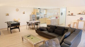 Een woonkamer met een tafelvoetbalspel, een bank en een salontafel.