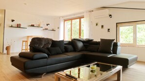 Een moderne woonkamer met een hoekbank, een glazen salontafel en een houten vloer.