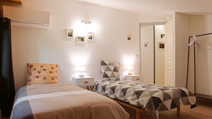 Een slaapkamer met twee bedden, nachtkastjes, wandlampen en een kledingkast.