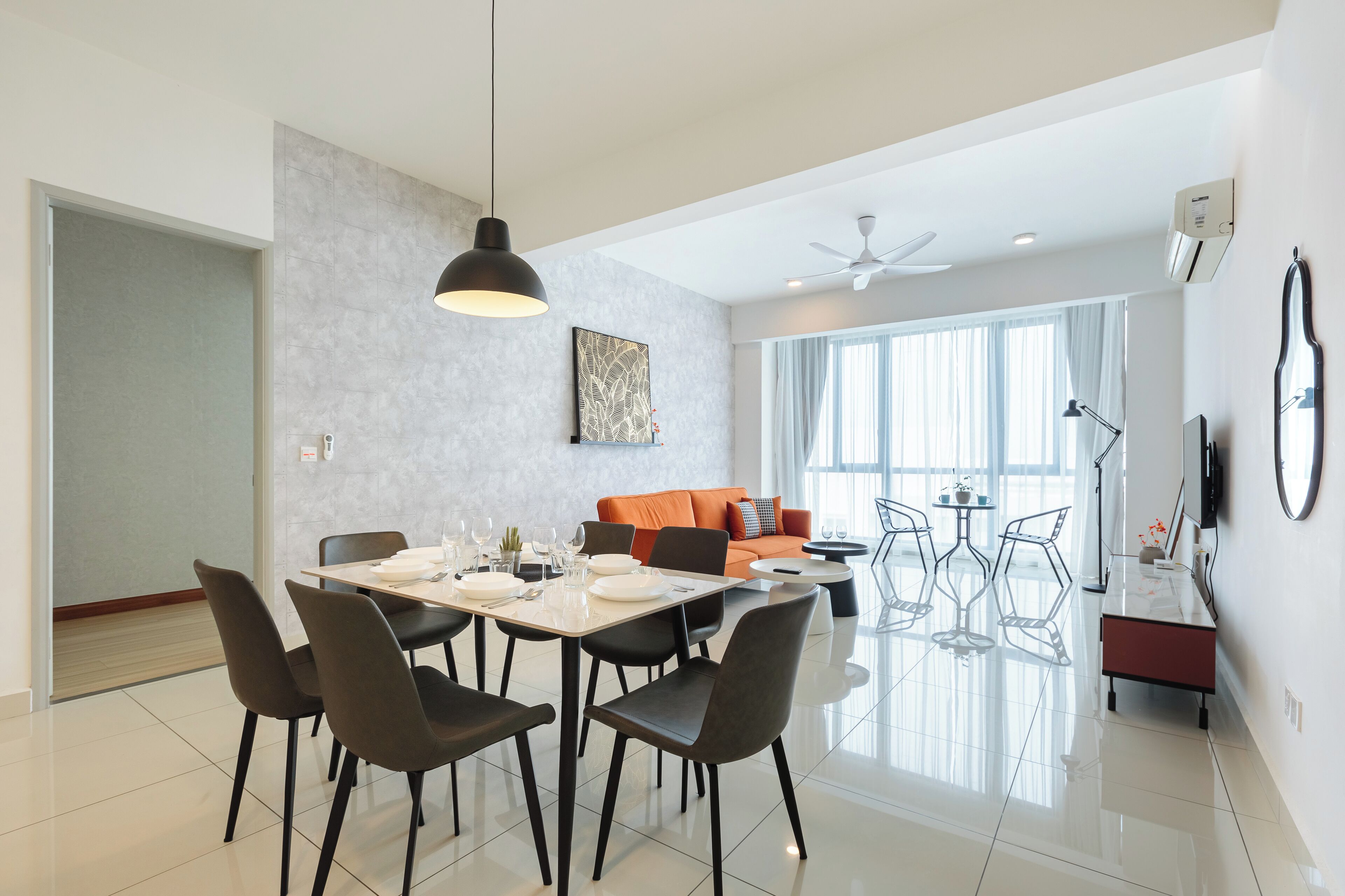 Un comedor moderno con una mesa para cuatro, un sofá y un televisor al fondo.
