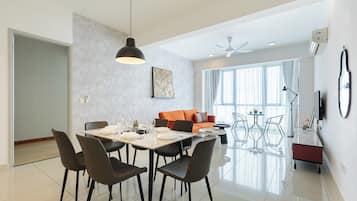 Un comedor moderno con una mesa para cuatro, un sofá y un televisor al fondo.