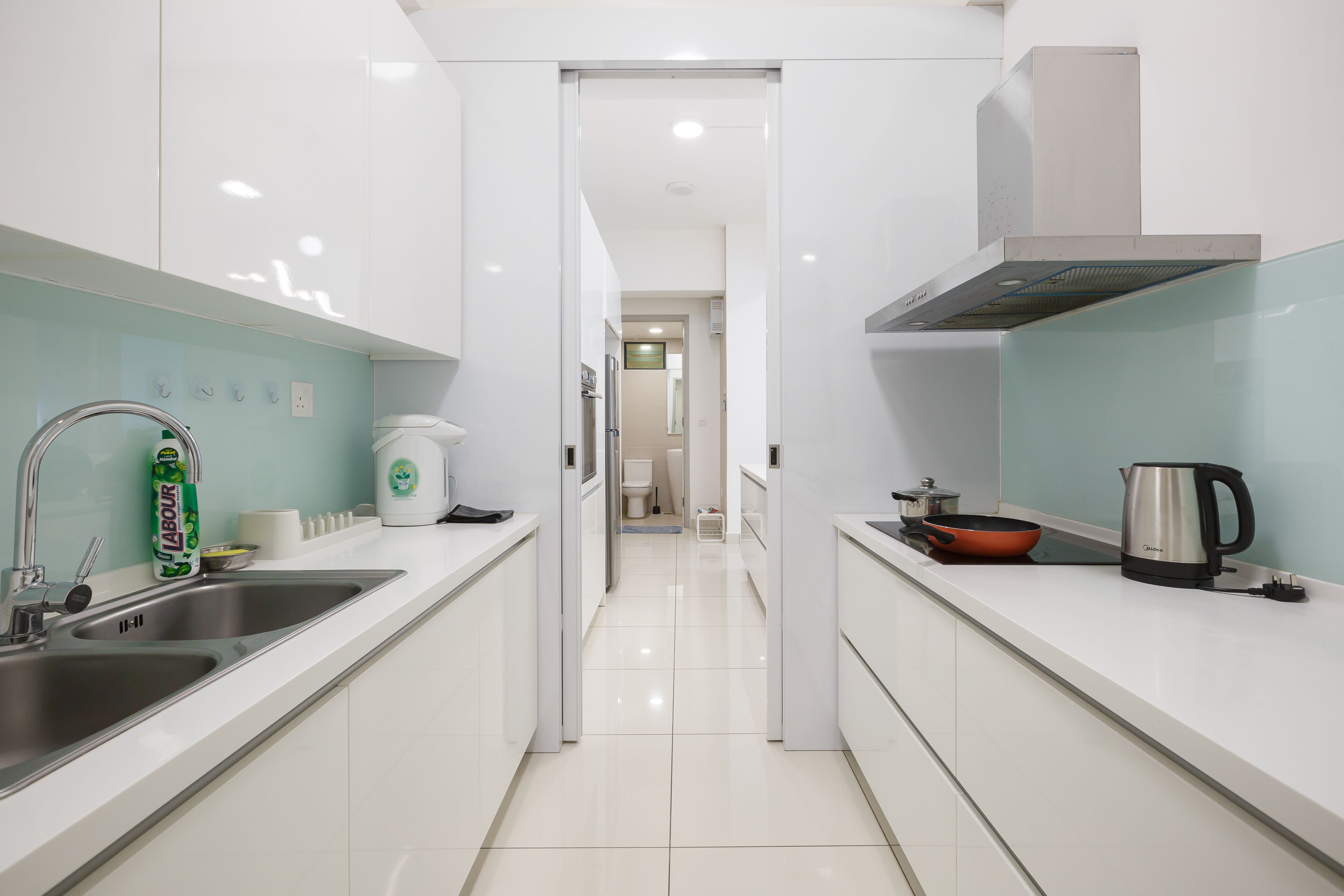 Una cocina moderna con armarios blancos, electrodomésticos de acero inoxidable y un diseño luminoso y limpio.