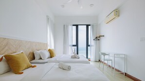 A hotel room with two beds, a desk, and a view of the sea. - The Jazz Serviced Suites (George Town)