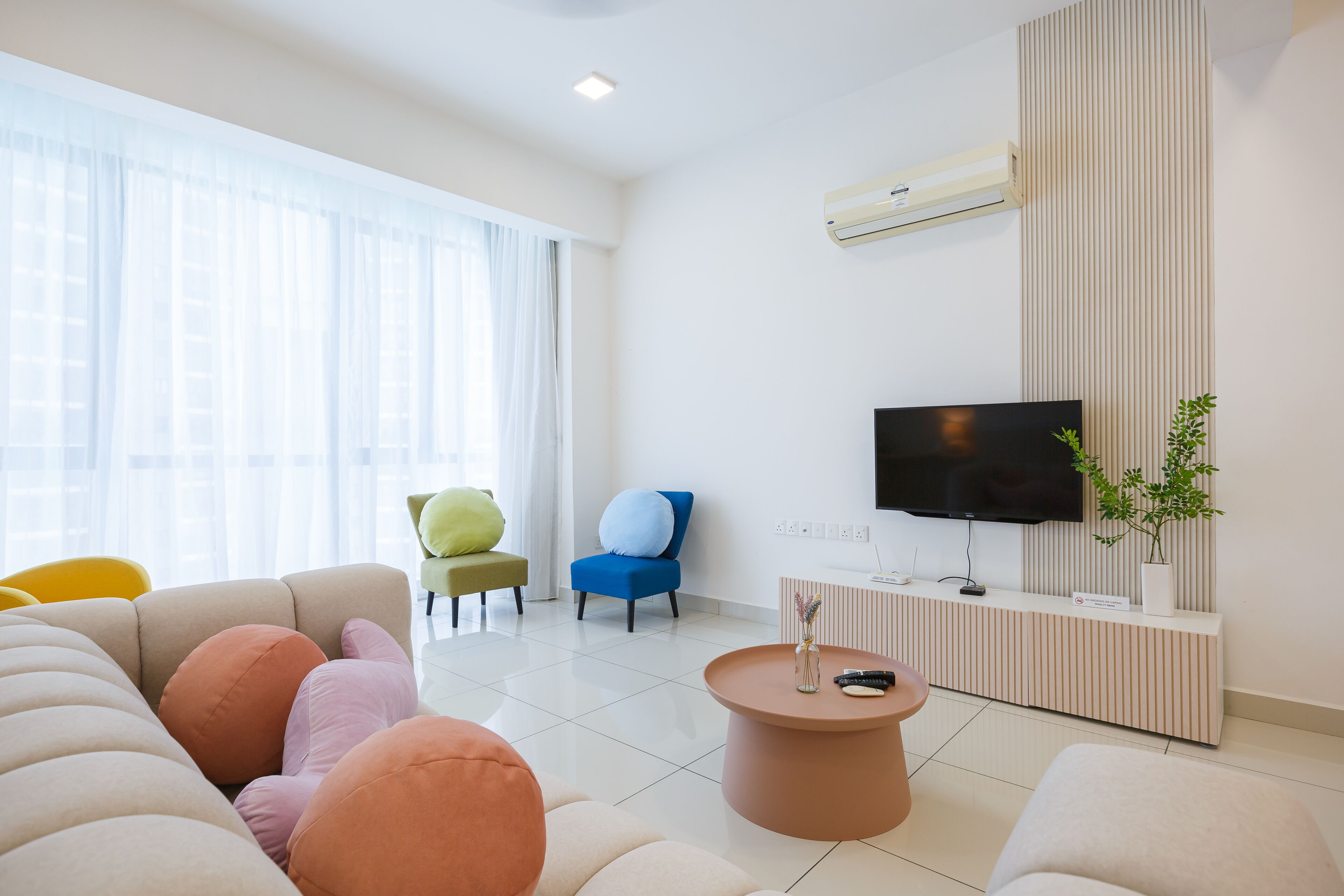 Una sala de estar moderna con un sofá, sillas, una mesa de centro, un televisor y una planta en maceta.