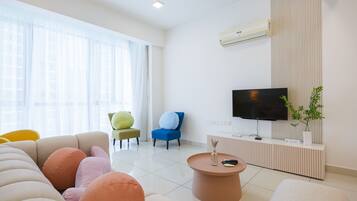 Una sala de estar moderna con un sofá, sillas, una mesa de centro, un televisor y una planta en maceta.