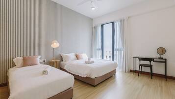 Une chambre d’hôtel avec deux lits, un bureau, une chaise, un ventilateur de plafond et une grande fenêtre avec des rideaux.