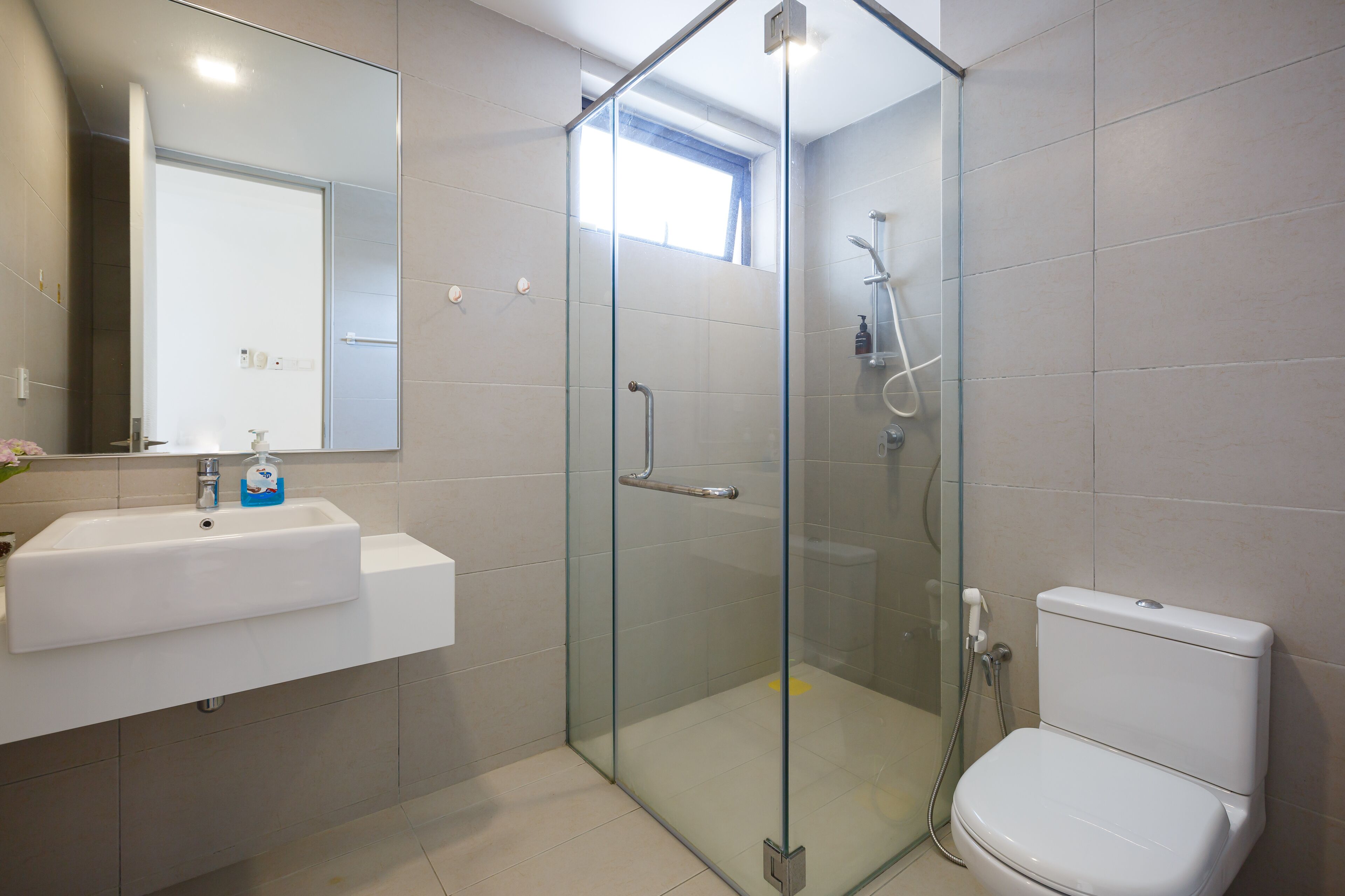 A modern bathroom with a glass-enclosed shower, a white sink, and a toilet.
