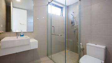 A modern bathroom with a glass-enclosed shower, a white sink, and a toilet.