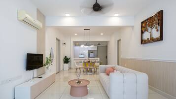 Uma sala de estar moderna com um sofá branco, uma mesa de centro rosa e uma televisão de tela plana na parede.